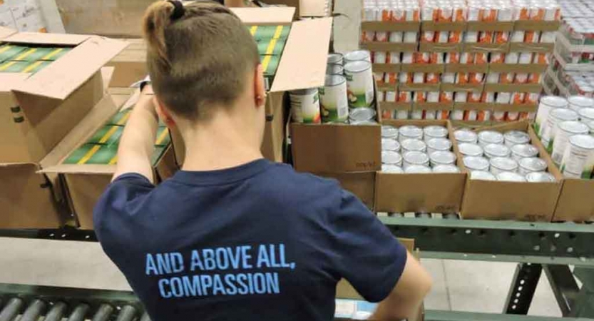 a person packs boxes of food as part of a service project with outward bound